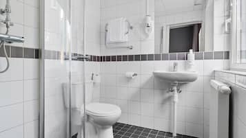 A modern bathroom with a glass shower enclosure, a white toilet, a sink with a soap dispenser, and a radiator.