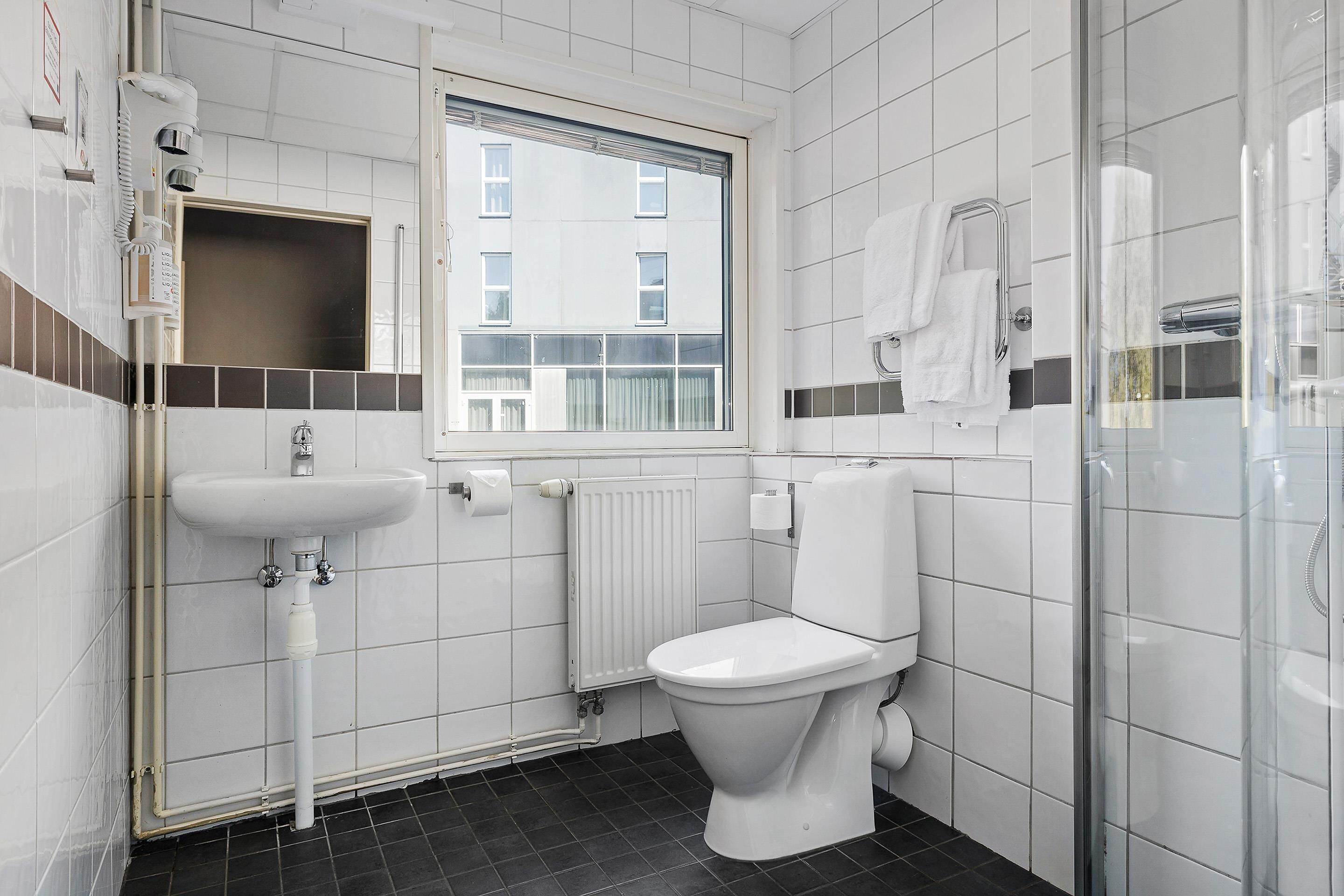 Un baño moderno con inodoro, lavamanos y ventana.