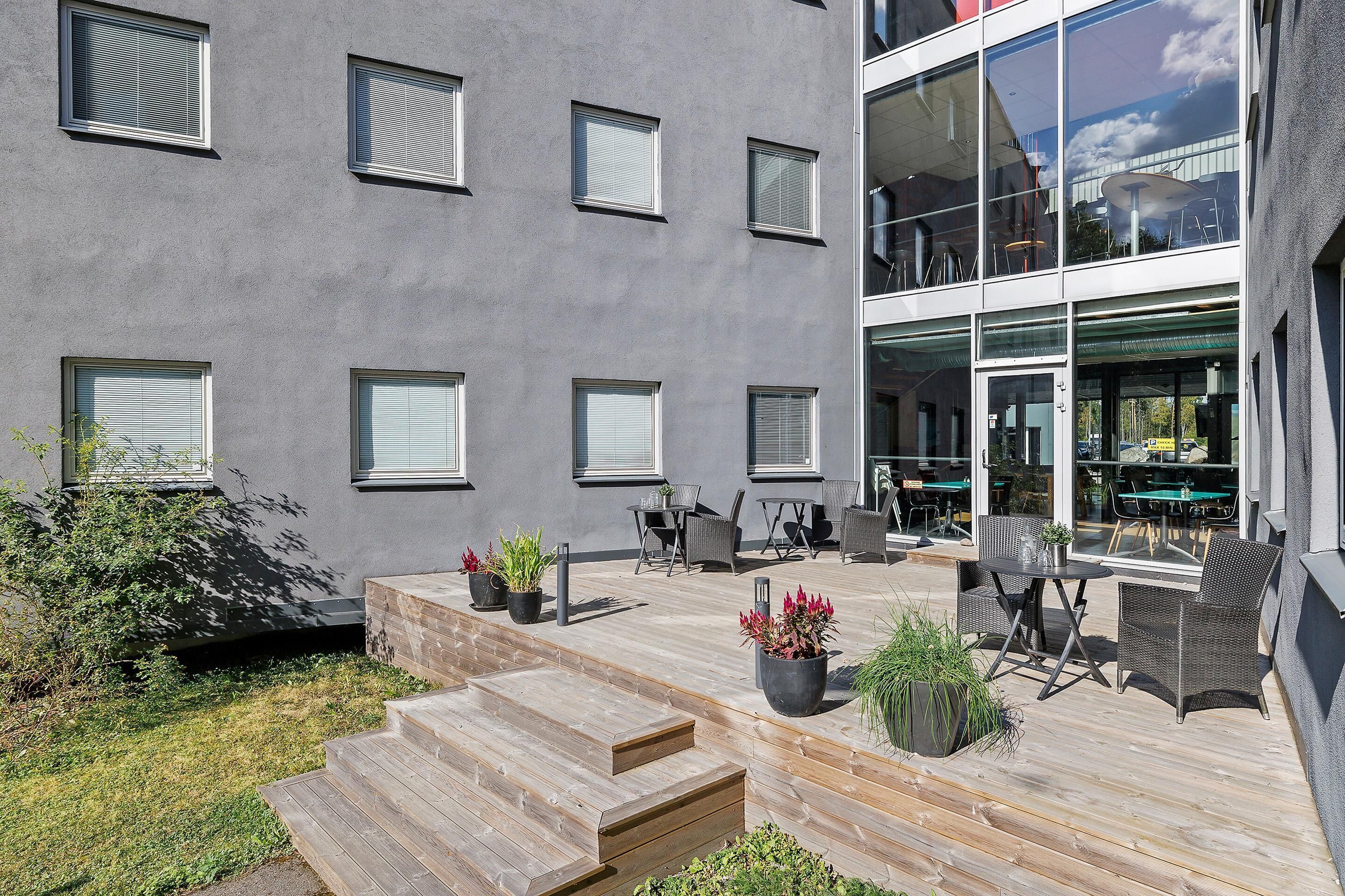 Un edificio con varias ventanas, mesas al aire libre y una terraza de madera.