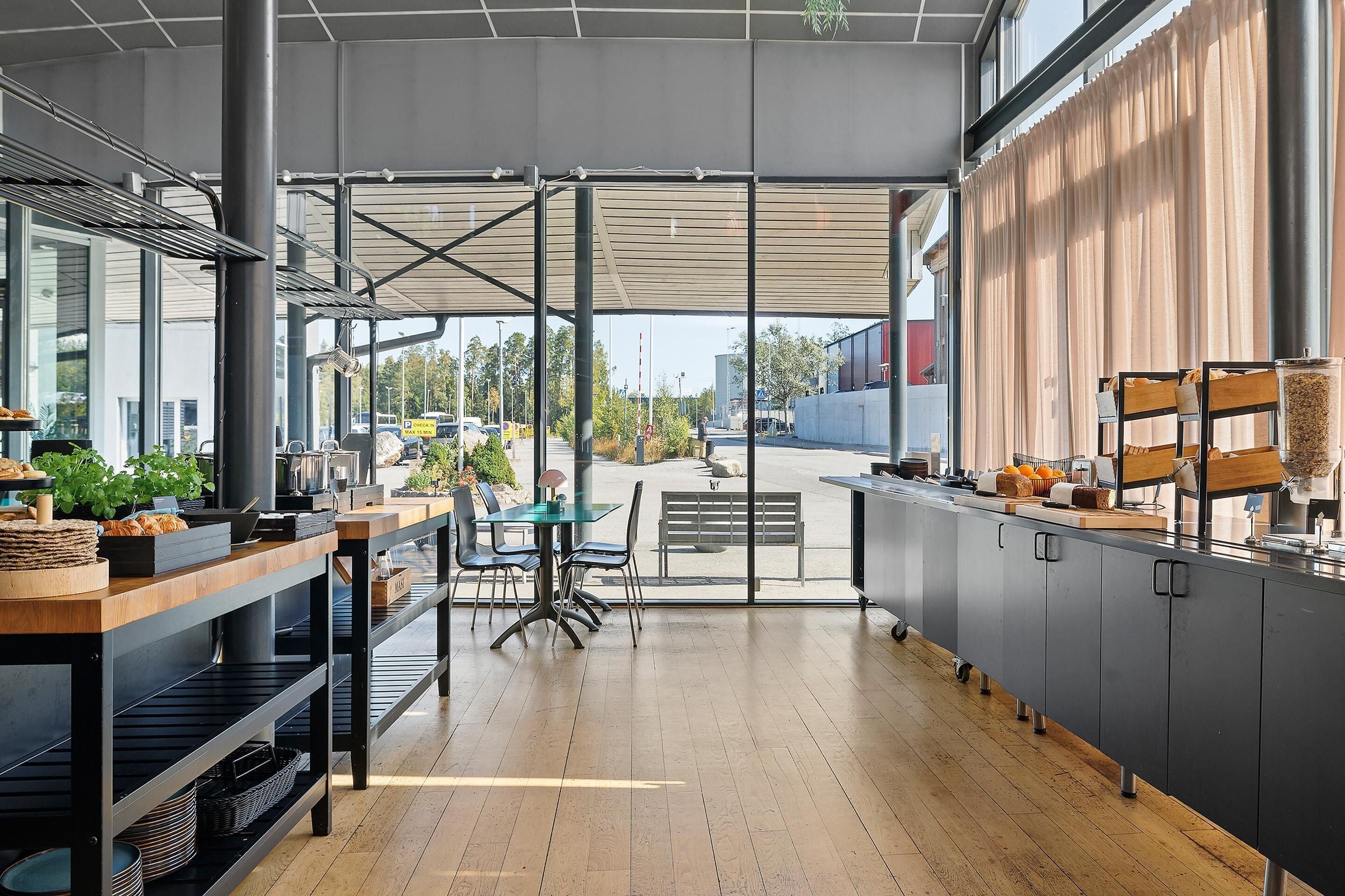 A modern kitchen with a wooden floor, a dining area with chairs, and a view of the street outside.
