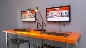 A workspace with two monitors, a desk, and two chairs.