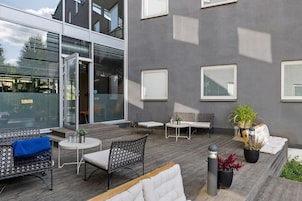 An outdoor seating area with wicker furniture, a small table, and potted plants.