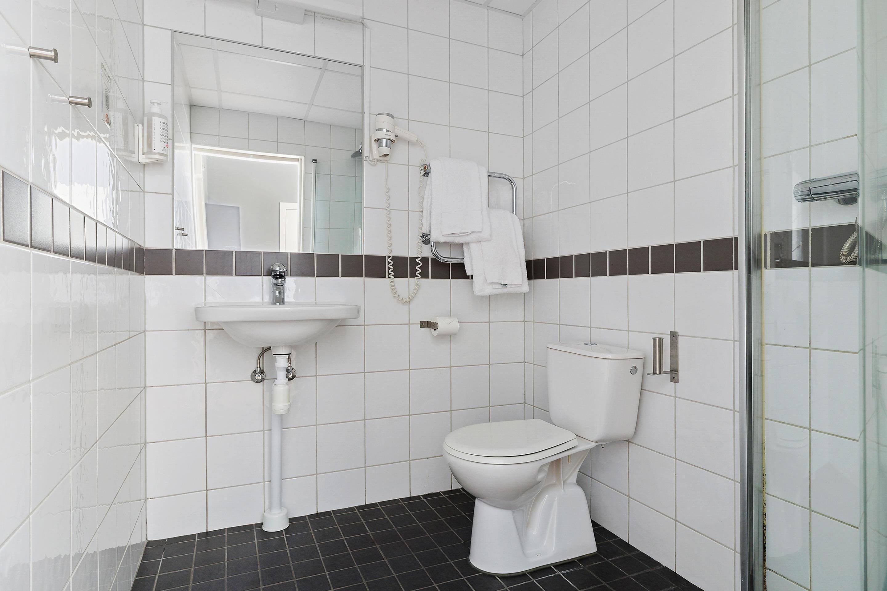 A modern bathroom with a white sink, toilet, and a glass shower enclosure.