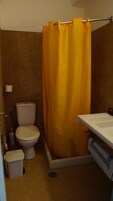 A bathroom with a toilet, a shower curtain, a sink, and a towel rack.