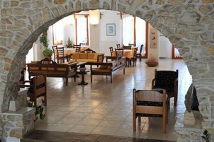 A spacious lobby with stone arches, wooden furniture, and a tiled floor.