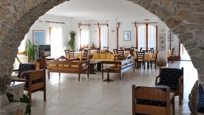 A spacious indoor area with stone arches, wooden furniture, and large windows allowing natural light.