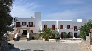 A white building with multiple balconies and a stone staircase leading to the entrance.