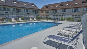 A swimming pool with lounge chairs and a fenced area, surrounded by apartment buildings. - Admiralty Inn & Suites - a Red Collection Hotel (East Falmouth)