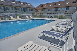 A swimming pool with lounge chairs and a fenced area, surrounded by apartment buildings. - Admiralty Inn & Suites - a Red Collection Hotel (East Falmouth)