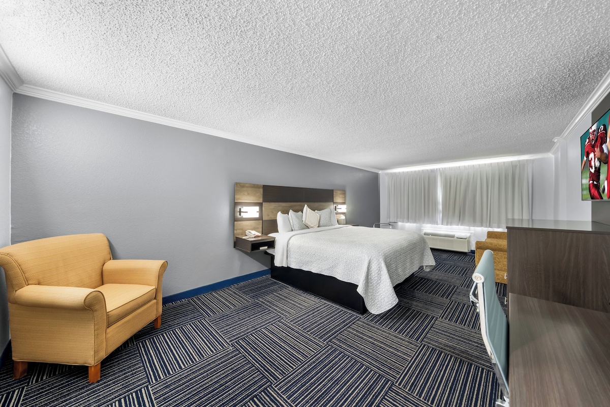 A hotel room with a bed, a sofa, a desk, and a TV.
