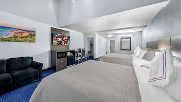 Une chambre d’hôtel avec un grand lit, un canapé, un bureau, une télévision et un tableau au mur.