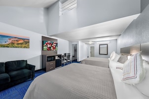 A hotel room with a large bed, a sofa, a desk, a TV, and a painting on the wall.