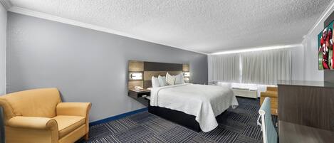 Habitación de hotel con cama, sofá, escritorio y televisor.
