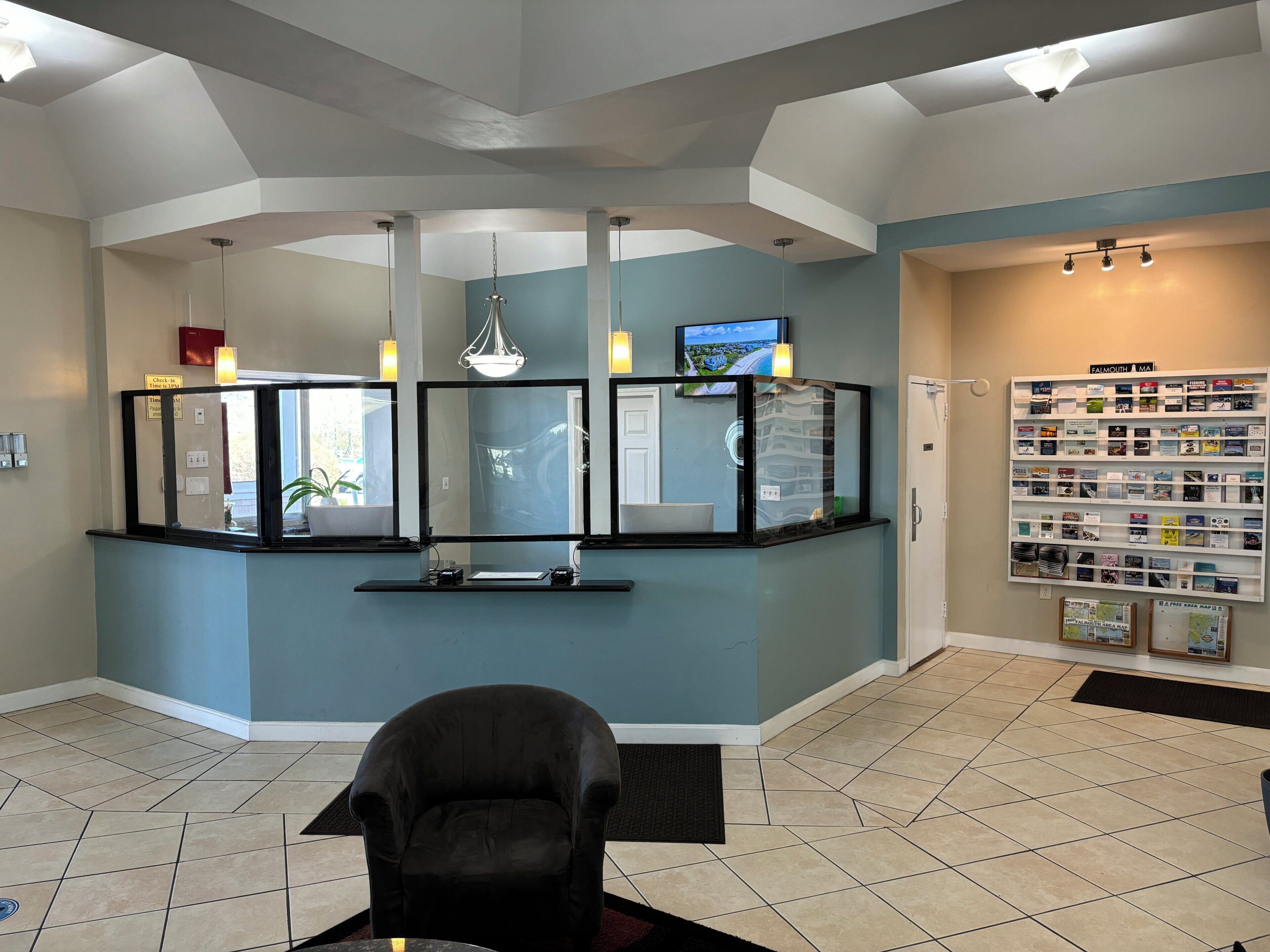 A reception area with a black leather chair, a reception desk with a computer, and a wall display of brochures.