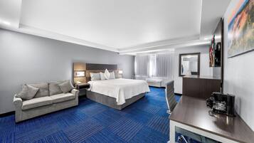 A hotel room with a bed, a sofa, a desk, and a coffee maker.