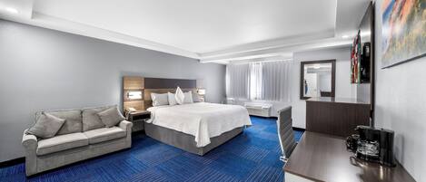 A hotel room with a bed, a sofa, a desk, and a coffee maker.