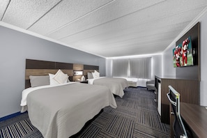 A hotel room with two beds, a desk, a TV, and a window with curtains. - Admiralty Inn & Suites - a Red Collection Hotel (East Falmouth)