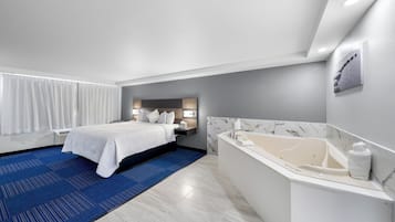 Una habitación de hotel moderna con una cama grande, un baño independiente con bañera y una alfombra azul.