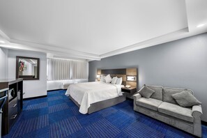 Ett hotellrum med en stor säng, en soffa, ett skrivbord och en spegel.