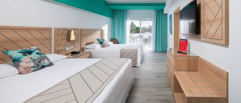 A hotel room with two beds, a ceiling fan, a TV, and a view of the outdoors.