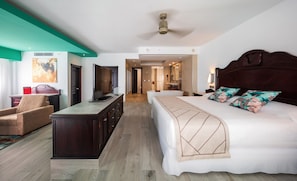 A hotel room with a bed, a desk, a TV, a bathroom, and a view of the hallway.