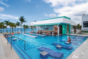 A swimming pool area with lounge chairs and a building with a green roof.