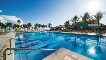 Relax by the pool surrounded by palm trees and lounge chairs.