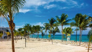 A beach volleyball court with palm trees and beach chairs. - Hotel Riu Ocho Rios - All Inclusive (Ocho Rios)