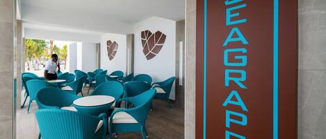 Vestíbulo de un hotel Seagrape con sillas color turquesa, mesas blancas y un cartel grande en la pared.