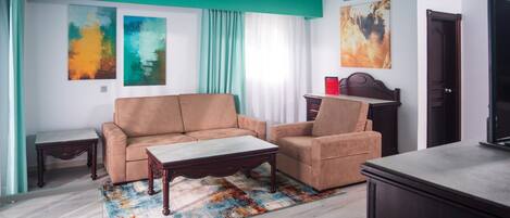 Una sala de estar moderna con una pared de acento color turquesa, un sofá, una mesa de centro y obras de arte.
