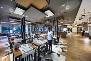 A modern restaurant with multiple dining areas, wooden flooring, and a variety of seating arrangements.
