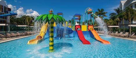 Una piscina con múltiples toboganes acuáticos y una estructura con palmeras.