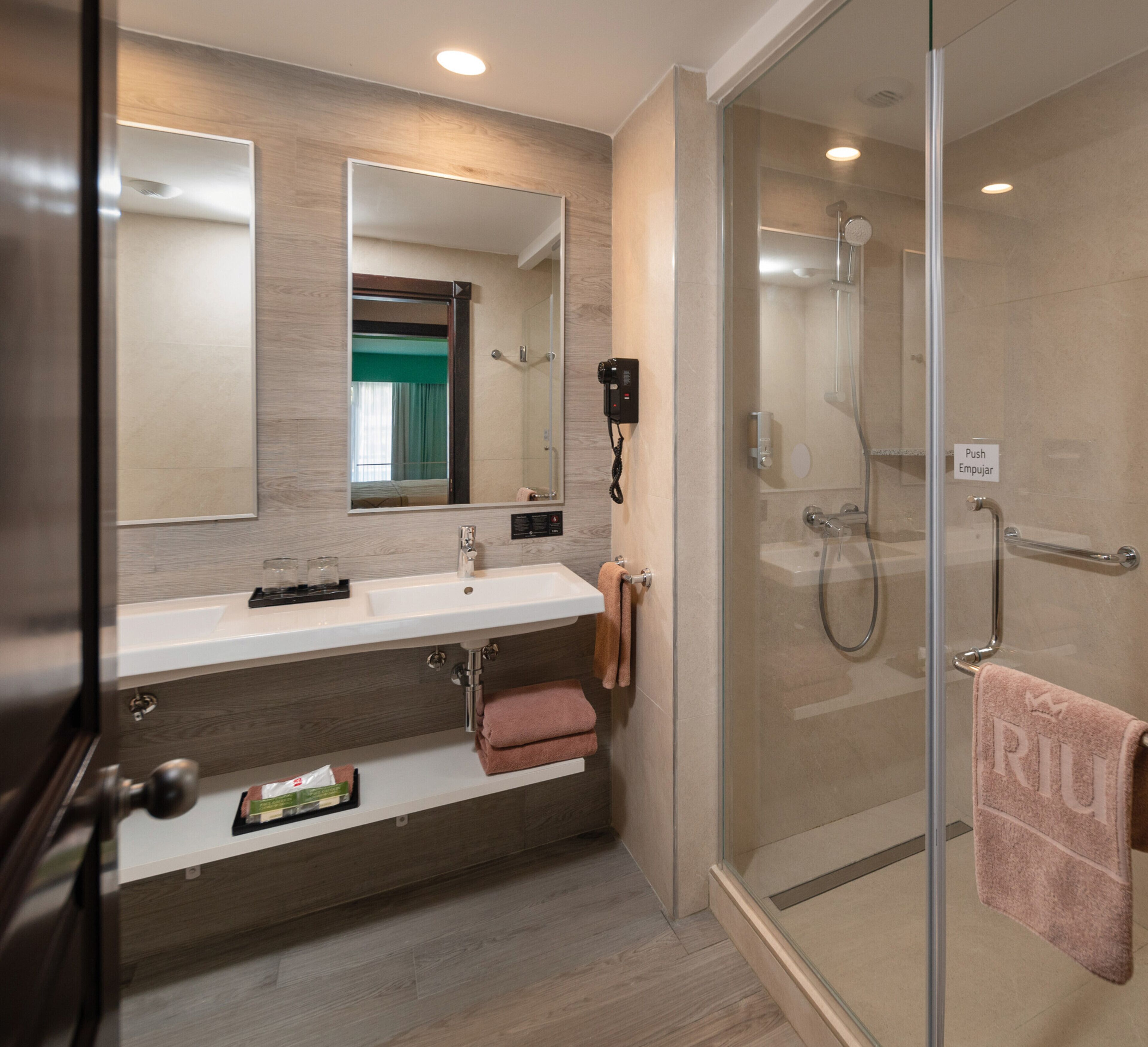 Une salle de bain moderne avec une douche à parois de verre, un meuble-lavabo avec un miroir et un porte-serviettes.