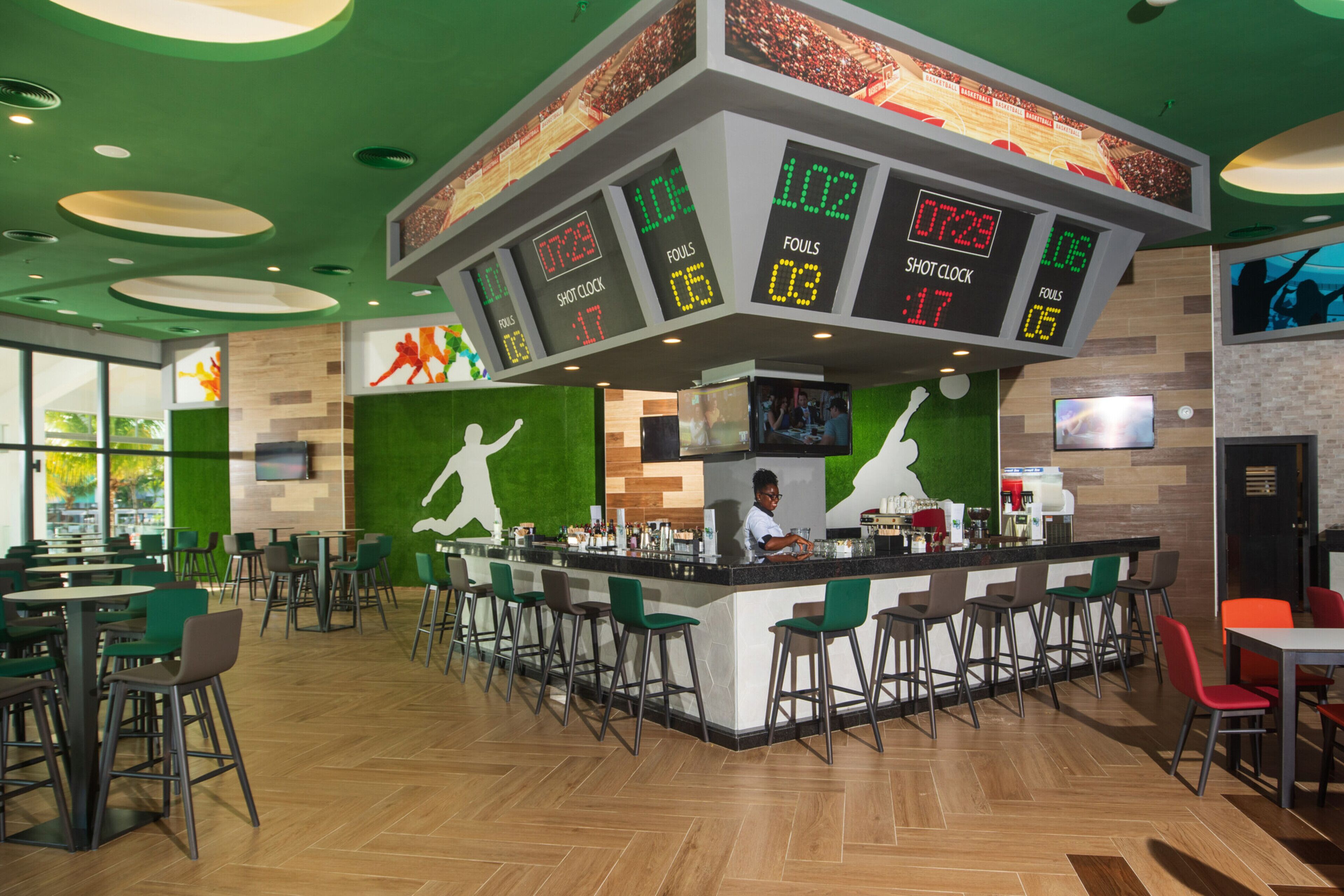 A sports bar with a digital scoreboard, bar area, and seating for patrons.