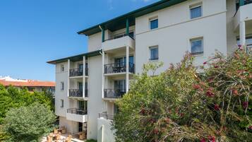 A multi-story building with balconies, outdoor seating, and greenery.
