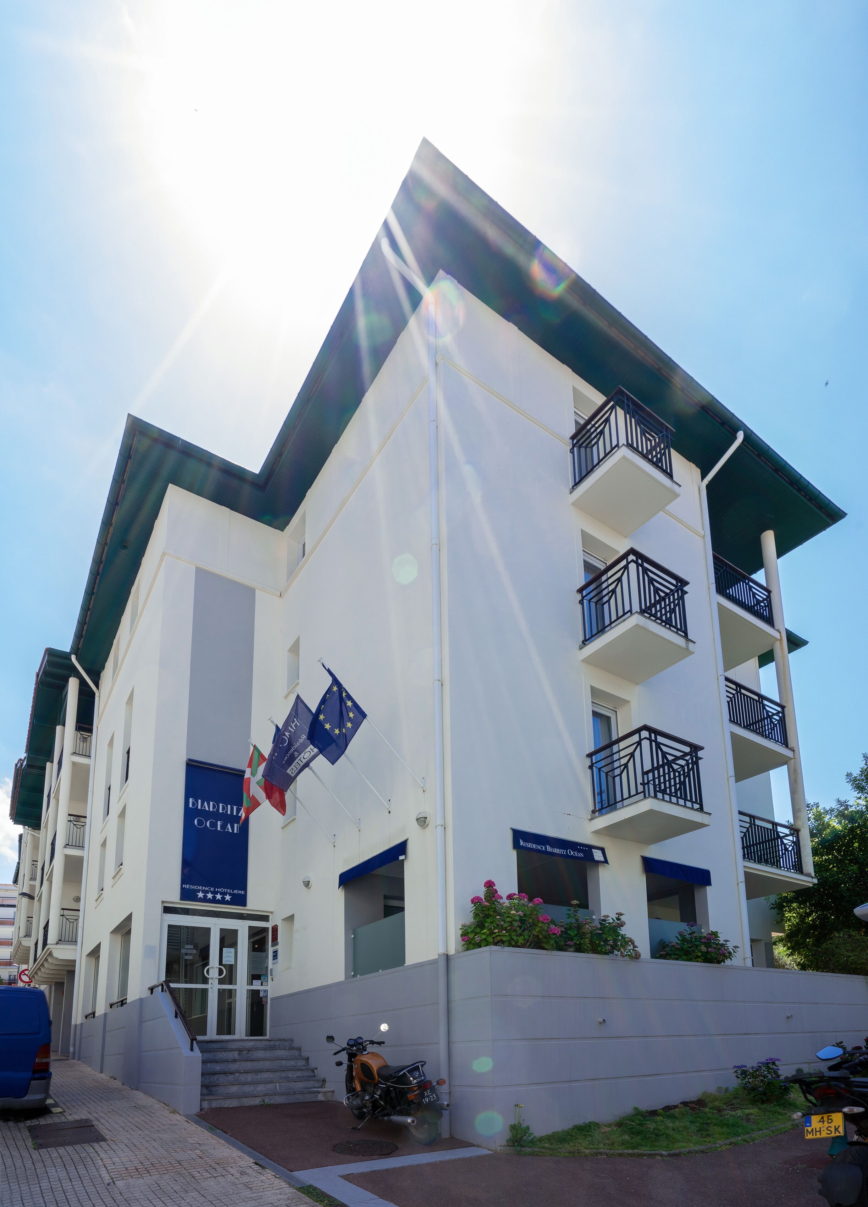 A multi-story hotel with balconies, a flag, and a sign indicating it is a residence hotel.