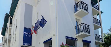 A multi-story hotel with balconies, a flag, and a sign indicating it is a residence hotel.