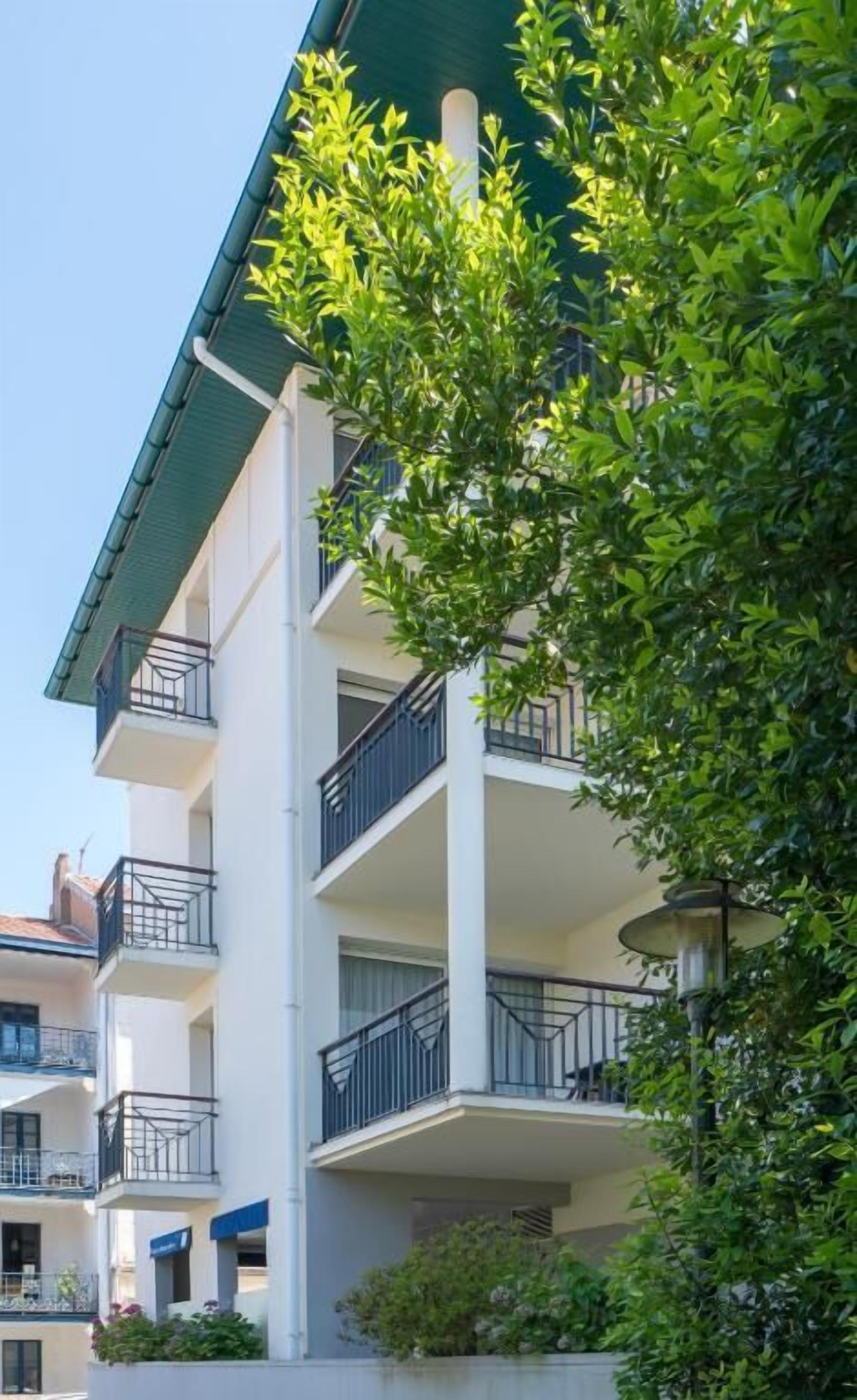 Un immeuble résidentiel à plusieurs étages, doté de balcons et d’un toit végétalisé.