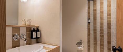 A bathroom with a sink, mirror, and shower.