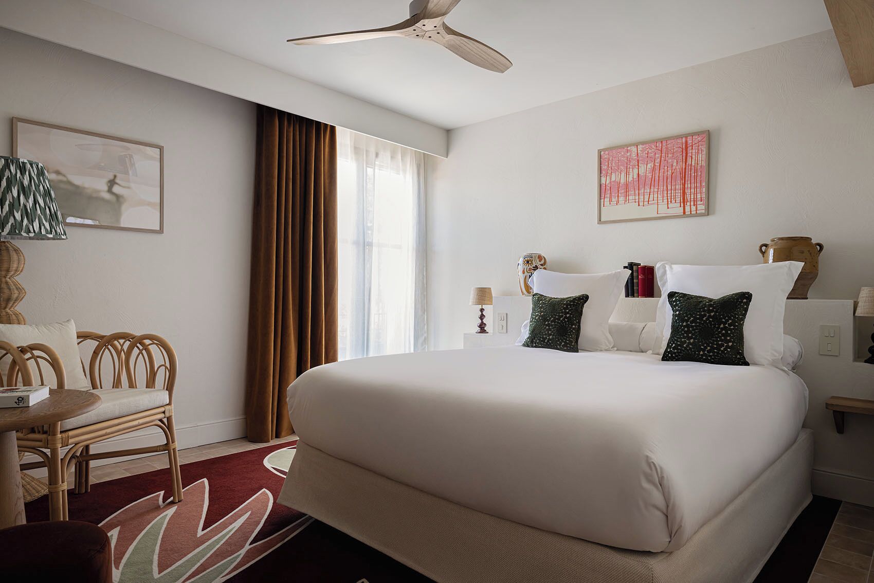 Ein Hotelzimmer mit einem großen Bett, einem Sessel, einem Schreibtisch und einem Deckenventilator.