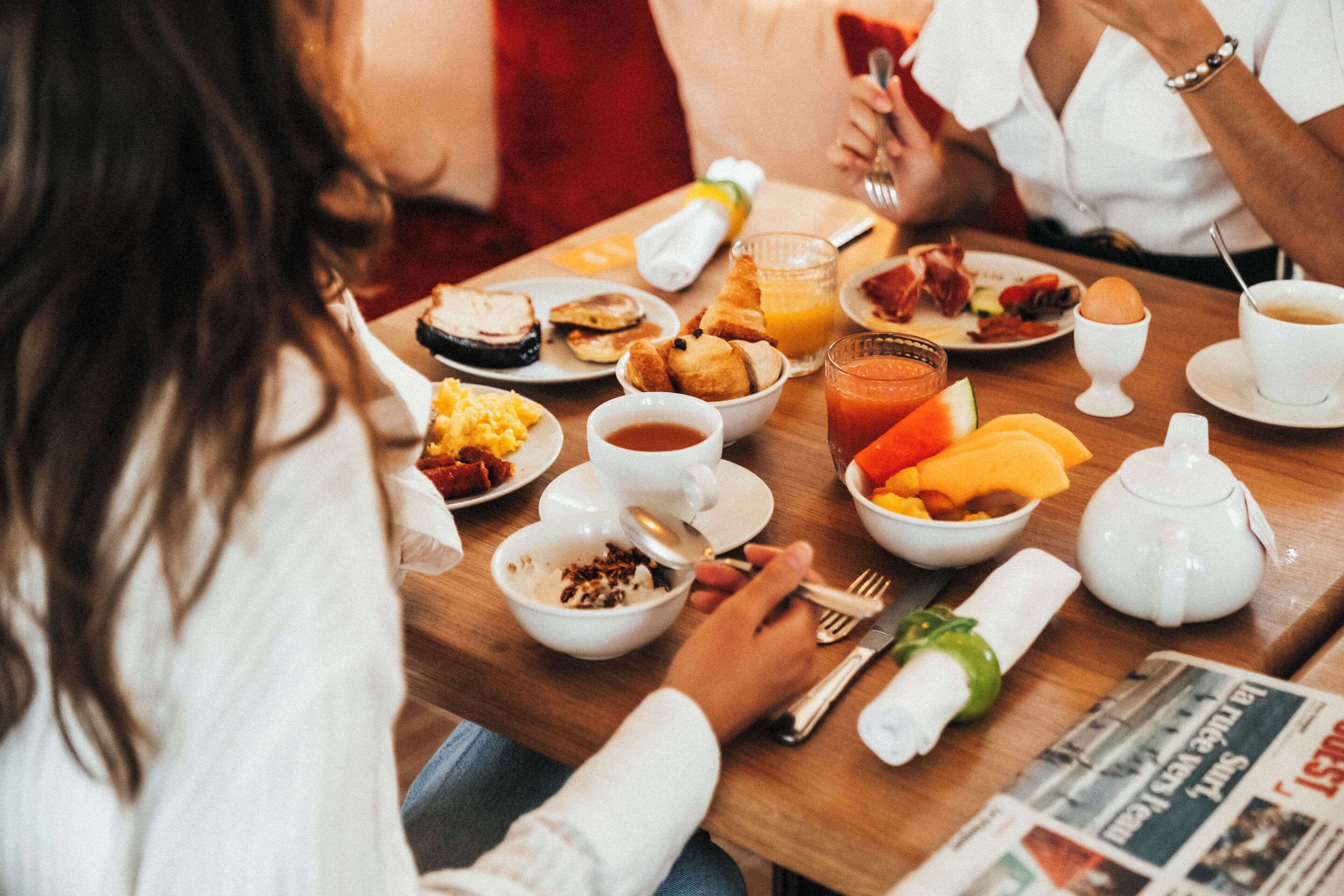 Ein Frühstückstisch mit verschiedenen Speisen, darunter Eier, Toast und Obst.
