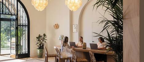 A reception area with a wooden reception desk, wicker chairs, and a large potted plant.