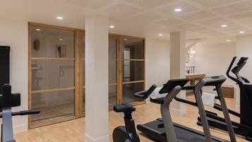 Een moderne sportschool met loopbanden, hometrainers en een spiegelwand.