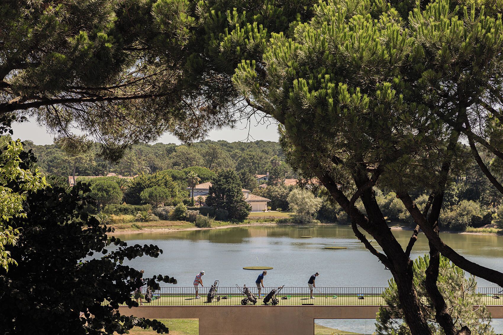 Un parcours de golf avec un lac, entouré d’arbres et avec des maisons en arrière-plan.
