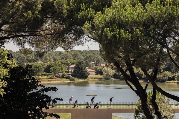 A golf course with a lake, surrounded by trees and houses in the background. - Hotel Maison Chiberta (Anglet)