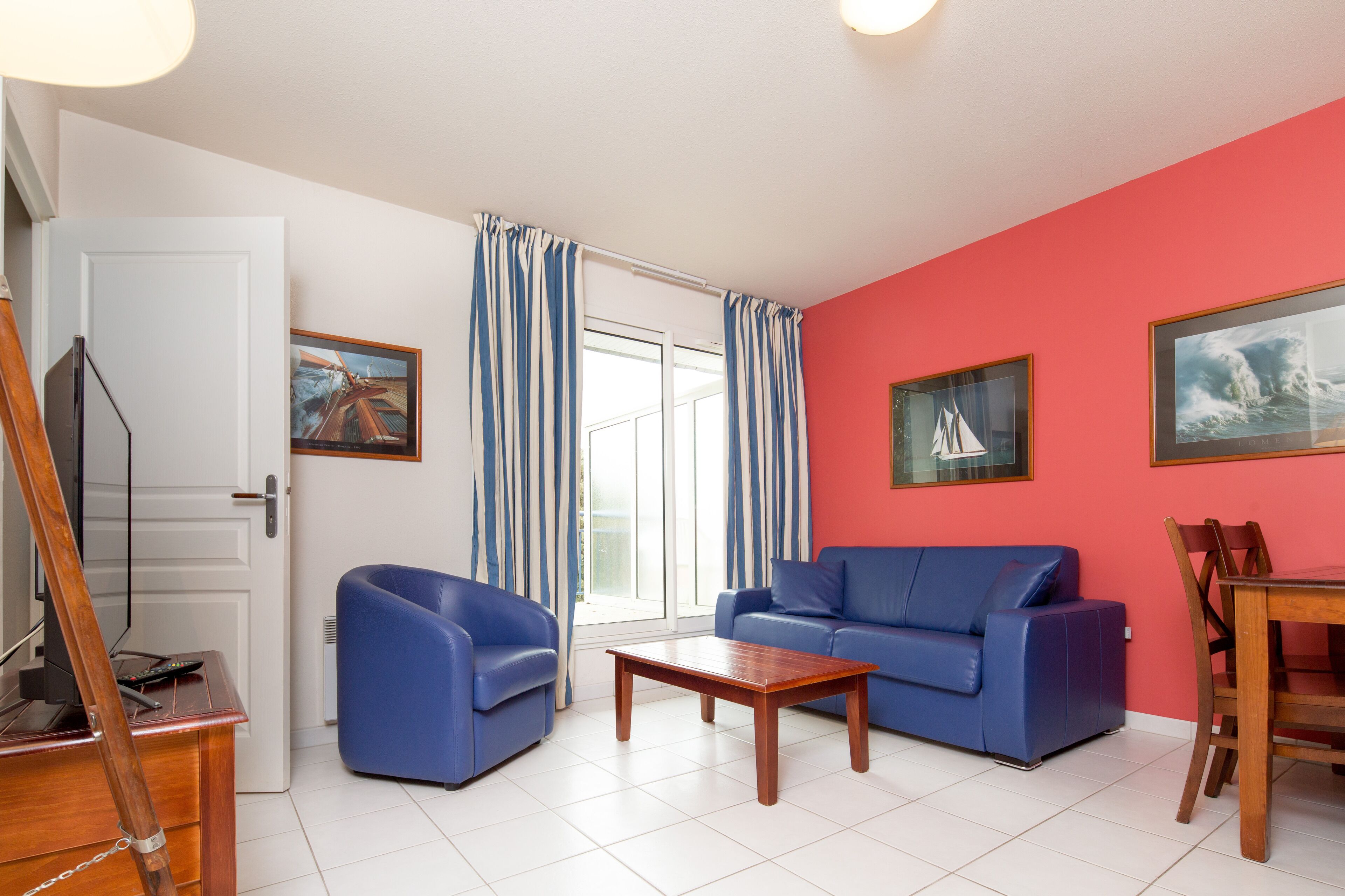 A living room with a blue sofa, a wooden coffee table, and a dining table with chairs.