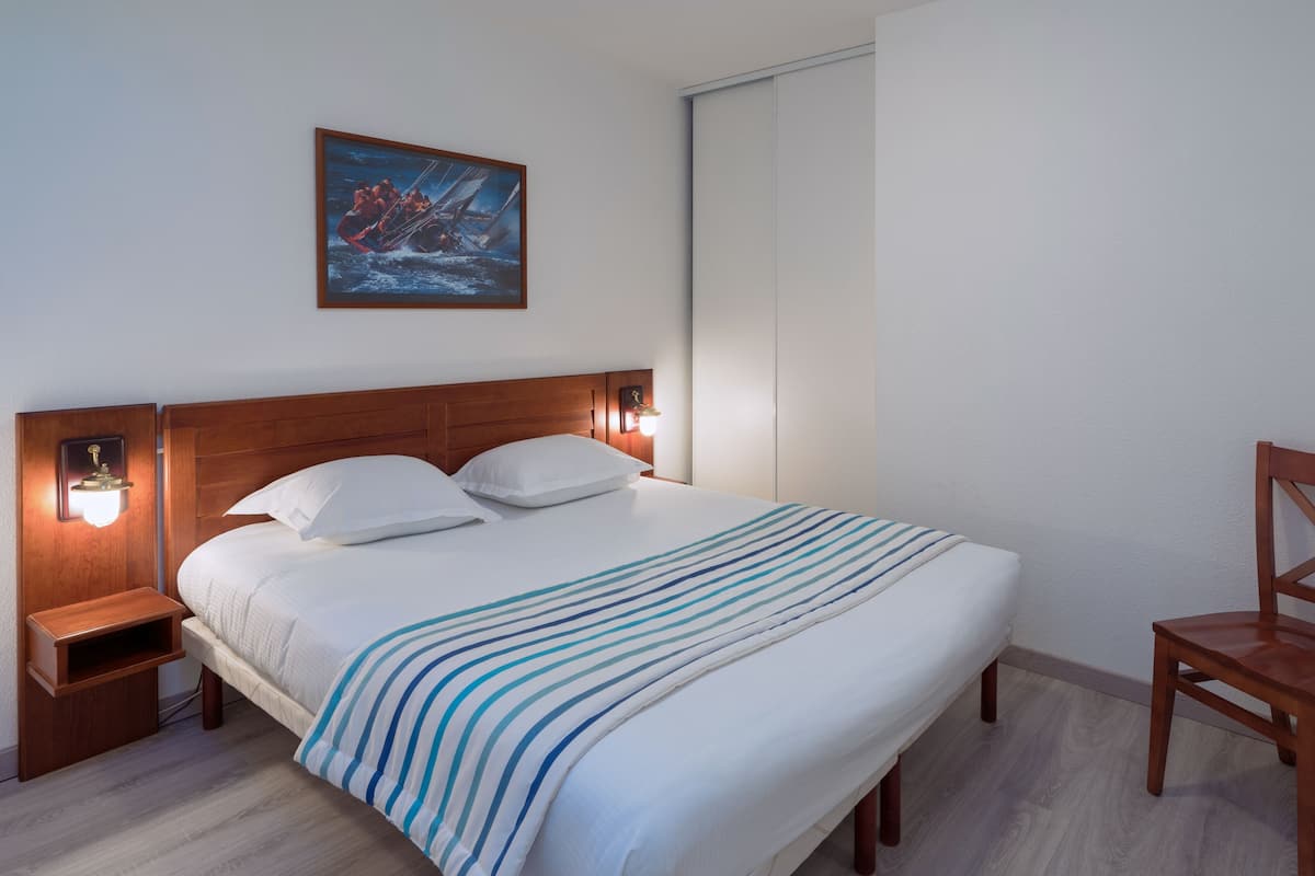 Una cama bien hecha con un edredón a rayas, un cabecero de madera y dos lámparas de noche.
