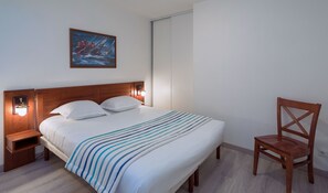 Una cama bien hecha con un edredón a rayas, un cabecero de madera y dos lámparas de noche.