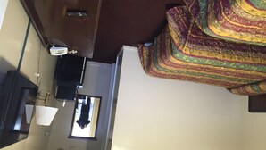 A room with a bed, a desk, a chair, a lamp, and a window. - Blue Falls Motel (Tonawanda)