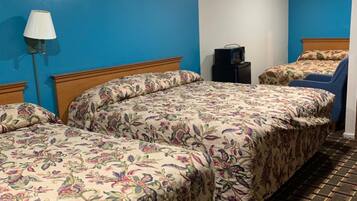 A hotel room with two beds, a lamp, a TV, and a patterned carpet.